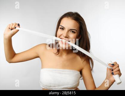 Junge schöne Frau zerreißt Gaze mit ihren Zähnen, isoliert auf weiß Stockfoto