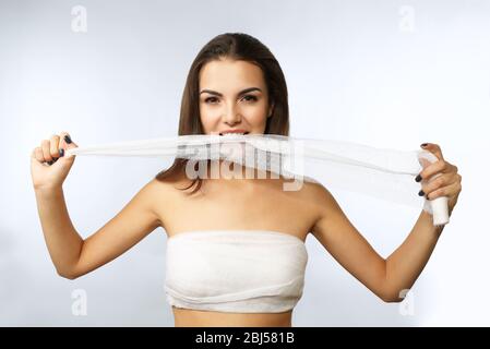 Junge schöne Frau zerreißt Gaze mit ihren Zähnen, isoliert auf weiß Stockfoto