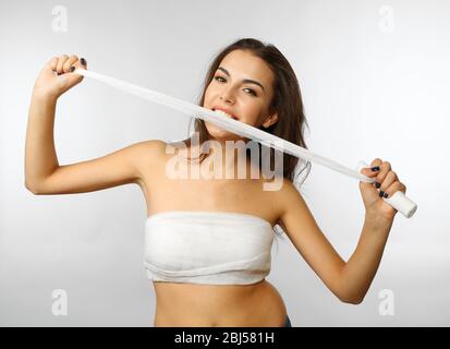 Junge schöne Frau zerreißt Gaze mit ihren Zähnen, isoliert auf weiß Stockfoto
