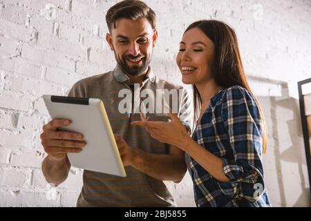Zwei glückliche Kollegen arbeiten im Büro mit einem Tablet Stockfoto