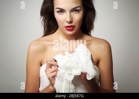 Junge schöne Frau, hält Gaze, auf grauem Hintergrund Stockfoto