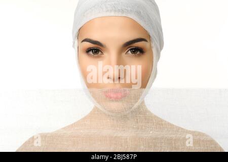 Junge schöne Frau mit einem Verband auf dem Kopf, hält Gaze, isoliert auf weiß Stockfoto