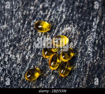 Fischöl. Vitamin E. Weichgel Kapsel. Fischöl. Vitamin E. Vitamin-Kapseln. Weiche Gel-Kapseln auf der Oberfläche von Naturstein. Stockfoto