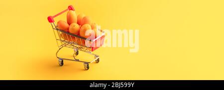 Kumquat kumquat oder in einem Warenkorb auf gelbem Hintergrund, Obst shopping Konzept Stockfoto