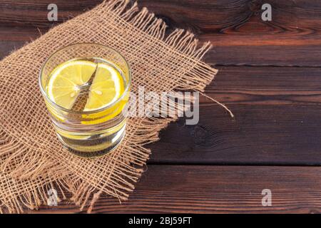 Glas mit Wasser und Zitrone auf Holztisch Stockfoto