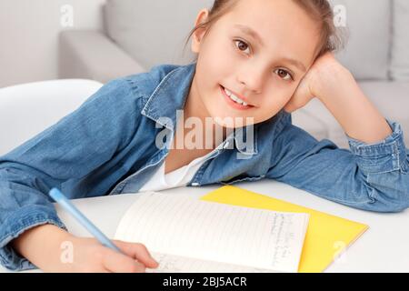 Charmante und junge Mädchen sitzt hinter dem Tisch, machen Schule Arbeit zu Hause Stockfoto