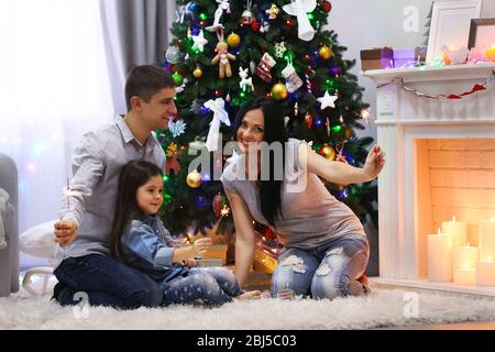 Glückliche Familie mit bengalischen Lichtern im dekorierten Weihnachtszimmer Stockfoto