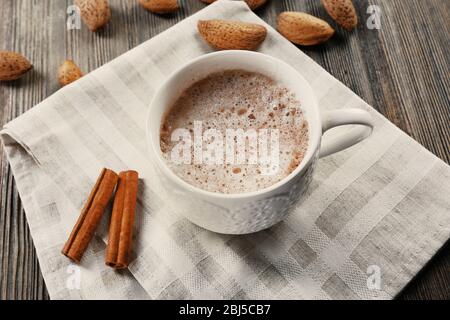 Tasse heißen Kakao auf Baumwollserviette mit Zimt und Mandeln Stockfoto