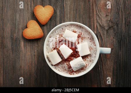 Tasse heißen Kakao mit Marshmallow und herzförmigen Plätzchen auf Holzhintergrund Stockfoto