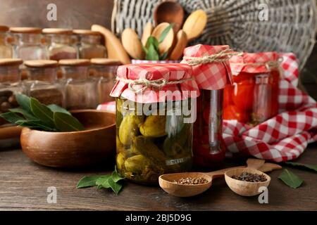 Gläser mit eingelegtem Gemüse und Bohnen, Gewürze, Buch der Rezepte und Küchenutensilien auf Holzhintergrund Stockfoto