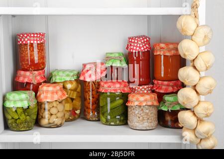 Gläser mit eingelegtem Gemüse und Bohnen auf Holzregal Stockfoto