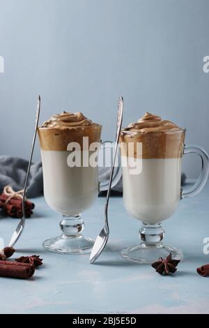 Dalgona cremiger Kaffee in zwei Gläsern auf blauem Hintergrund mit Schlagschaum. Koreanischer Kaffee Trend, Nahaufnahme, Vertikal-Format Stockfoto