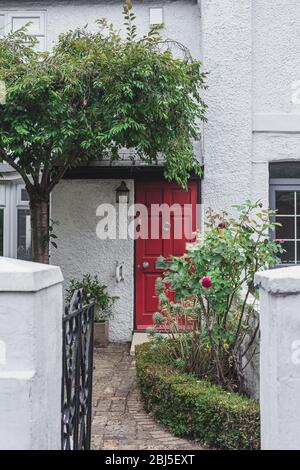 Farbenfrohe, leuchtend rote Tür an einer Fassade eines traditionellen englischen Reihenhauses in West Hampstead. Hampstead hat einige der teuersten Gehäuse in der Stockfoto