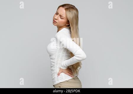 Junge Frau, die nach der Arbeit Schmerzen, Muskeln oder chronische Nervenschmerzen im Rücken hat. Gesundheitsproblem, Erkrankungen des Bewegungsapparates Konzept. Scoli Stockfoto