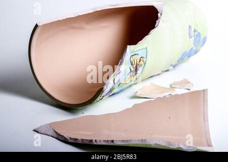 Gebrochene Porzellanvase liegend auf weißem Hintergrund Stockfoto