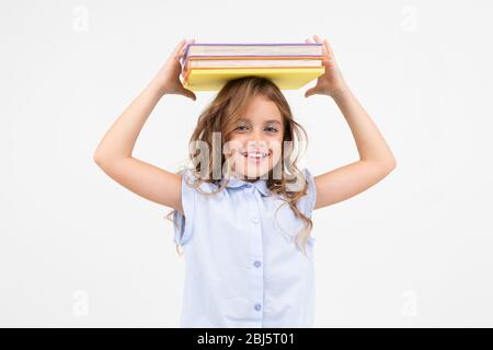 Mädchen Schulmädchen mit einem Berg von Büchern für Wissen isoliert auf weißem Hintergrund mit Kopierraum. Stockfoto