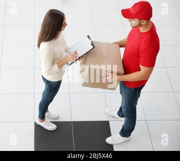 Empfang Paket - Lieferung Mann gibt Paket an junge Frau Stockfoto