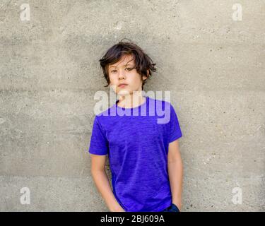 Porträt eines schönen Jungen mit intensivem Blick gegen lehnt Eine Wand Stockfoto