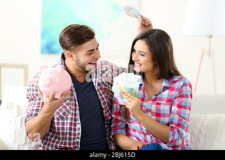 Glückliches Paar zu Hause sitzen und Geld aus dem Schwein Geldbox zählen Stockfoto