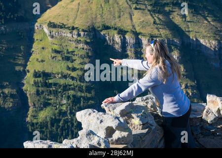 Eine Frau, die mit dem Finger auf einen Ort des Ordesa-Nationalparks zeigt. Sie bewundert von der Spitze eines Balkongebirges das ganze Tal, das Grün Stockfoto