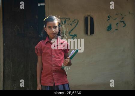 Mädchen auf dem Land, das Bücher für die Schule bereithält. Indien Stockfoto