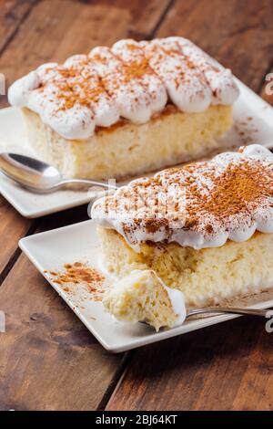 Zwei Stücke eines köstlichen drei Milchkuchen Dessert auf einem hölzernen Hintergrund Stockfoto