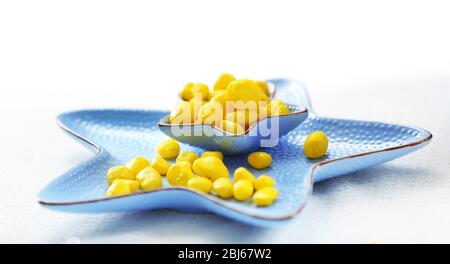 Gelbe Bonbons in blauer Sternschale auf dem Tisch Stockfoto