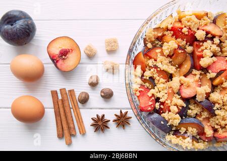 Bröseln Sie Pflaume hausgemachte Kuchen Zutaten auf weißen Holztisch, Draufsicht. Stockfoto