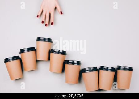 Schöne Hände folgen auf Pappbecher auf Pastellgrund. Konzept der Entfernung. Flacher Laienstil. Stockfoto