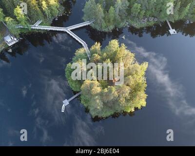 Luftaufnahme zum Pier mit einem Boot mit reflektierenden Wolken im Wasser, auf einer kleinen grünen Insel Stockfoto