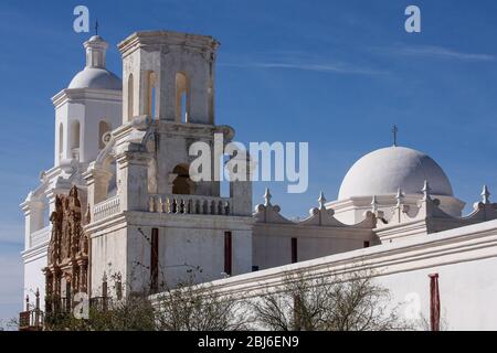 Zwei weiße Kirchtürme und eine Kuppel sind in der Mission San Xavier del Bac südlich von Tucson, Arizona, vor einem blauen Himmel zu sehen. Stockfoto