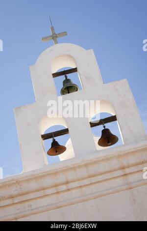 Drei Kirchenglocken hängen unter einem Kreuz in einem Glockenturm in der Mission San Xavier del Bac südlich von Tucson, Arizona. Stockfoto