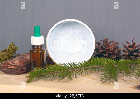 Ökologische Körperpflegekosmetik, Körperpeeling und ätherische Öle, Tannenzapfen und Zweig auf grauem Hintergrund. Stockfoto