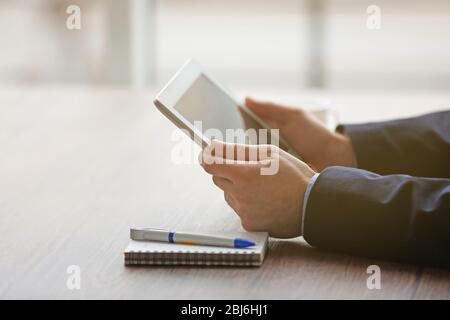 Die Hände des Mannes mit Tablet am Tisch Stockfoto