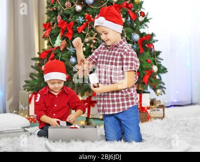 Zwei süße kleine Brüder Eröffnung Geschenke auf Weihnachtsdekoration Hintergrund Stockfoto