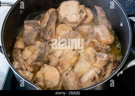 Hühnchen geschmortes Fleisch in einer Pfanne. Rustikales hausgemachtes Eintopf Fleisch. Blick von oben mit Rauch. Kochen Sie zu Hause. Stockfoto