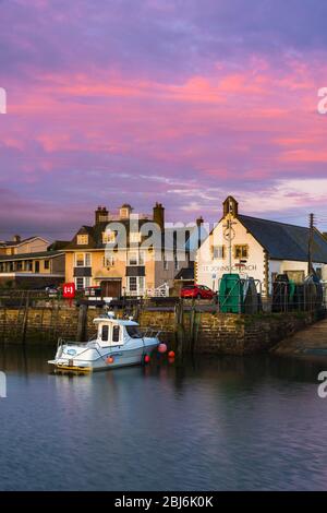 West Bay, Dorset, Großbritannien. April 2020. Wetter in Großbritannien. Der Himmel leuchtet orange, wenn die Wolken über dem Hafen bei Sonnenuntergang im Seebad West Bay in Dorset nach einem Tag mit leichtem Regen und bewölktem Himmel zu klar werden beginnen. Bild: Graham Hunt/Alamy Live News Stockfoto