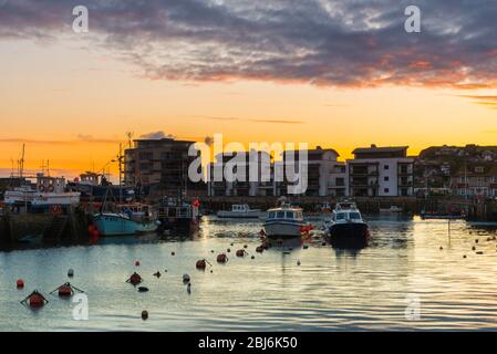 West Bay, Dorset, Großbritannien. April 2020. Wetter in Großbritannien. Der Himmel leuchtet orange, während die Wolken über dem Hafen bei Sonnenuntergang im Seebad West Bay in Dorset nach einem Tag mit leichtem Regen und bewölktem Himmel klar werden. Bild: Graham Hunt/Alamy Live News Stockfoto