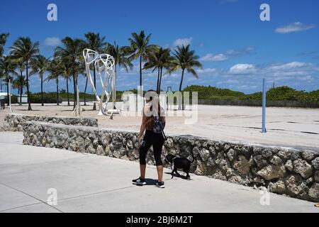 Miami, Vereinigte Staaten Von Amerika. April 2020. MIAMI BEACH - FL APRIL 27:EINE Frau geht mit ihrem Hund auf der Promenade in South Beach, am Mittwoch Miami-Dade 6-wöchige Schließung Auftrag für Parks offiziell endet, ersetzt durch ein neues Set von Regeln zur Begrenzung der engen Begegnungen während der Coronavirus-Pandemie, am 27. April, 2020 in Miami Beach Florida. (Foto von Alberto E. Tamargo/Sipa USA) Quelle: SIPA USA/Alamy Live News Stockfoto