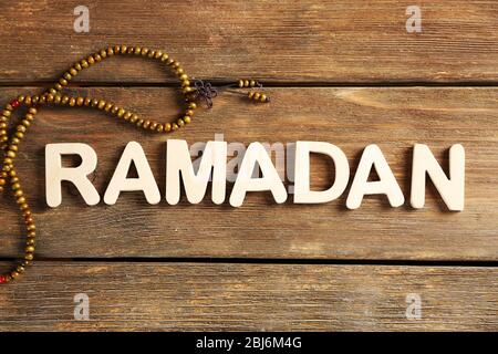 Bild des Wortes RAMADAN mit Rosenkranz auf Holzhintergrund, Nahaufnahme Stockfoto