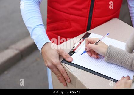 Weibliche Hand Signing Lieferform auf der Box, Nahaufnahme Stockfoto
