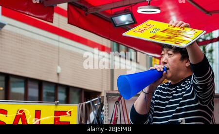Ein Verkäufer wirbt mit einem Bullhorn für sein Geschäft. Takeshita Straße im Harajuku Bezirk in Tokio, das Modezentrum für junge Leute Stockfoto
