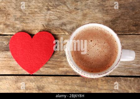 Tasse Kaffee mit roten Filzherzen auf Holzhintergrund, Nahaufnahme Stockfoto