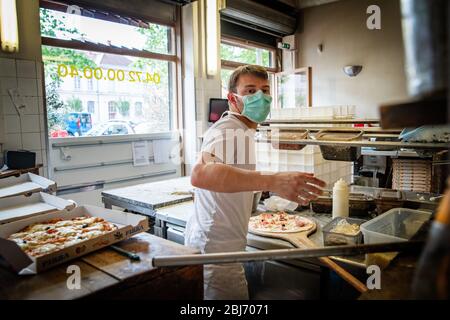 Mann arbeitet in einem Pizza-Restaurant-Laufwerk mit seiner Maske und covid 19 Schutz. Pandemiesituation Stockfoto