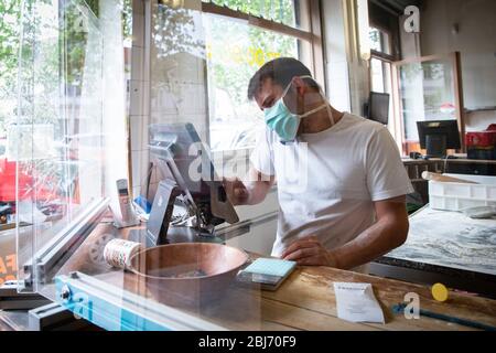 Mann arbeitet in einem Pizza-Restaurant-Laufwerk mit seiner Maske und covid 19 Schutz. Pandemiesituation Stockfoto