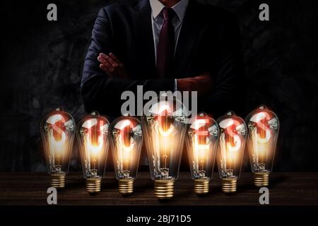 Erfolg und Business Innovation Idee Energie mit Glühbirne auf Holztisch und Geschäftsmann in dunklen Ton, erfolgreiche kreative Führer und Erfindung conce Stockfoto