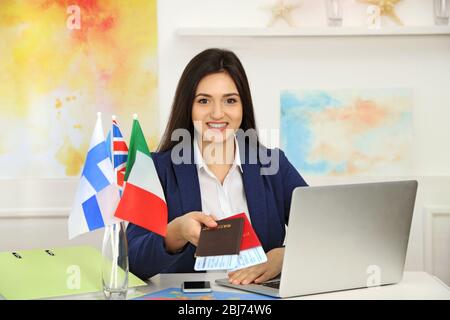 Junge Frau, die Pässe mit Tickets im Büro des Reiseunternehmens vorzeigt Stockfoto