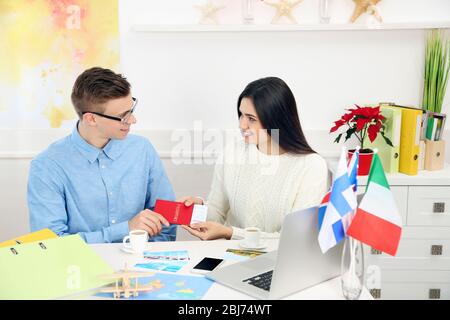 Agent, der im Büro des Reiseunternehmens jungen Frauen Pass und Ticket gibt Stockfoto