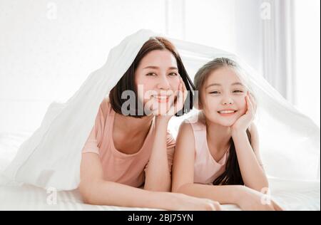 Schöne Mutter und Kind Mädchen entspannen und spielen im Bett Stockfoto