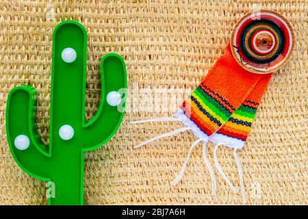 Cinco de Mayo Hintergrund. Ein Kaktus und ein Sombrero und Poncho auf einem Stroh ländlichen Tasche Hintergrundtextur Stockfoto